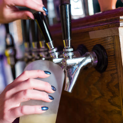 actively pouring a pint of a golden lager