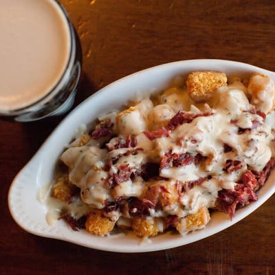 Loaded Irish Tater Tots and a glass of dark beer, top view