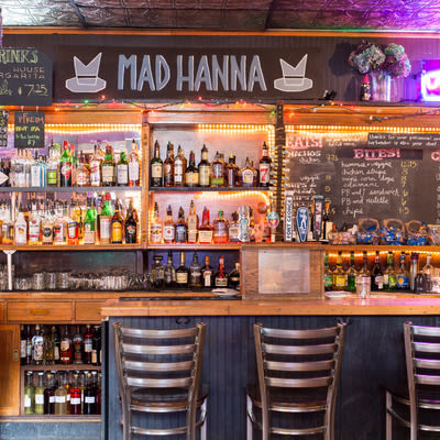 liquor bottles on a shelf and a chalkboard food menu behind the bar at Mad Hanna