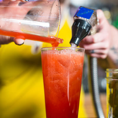 pouring campari from a tumbler into a pint glass and adding soda
