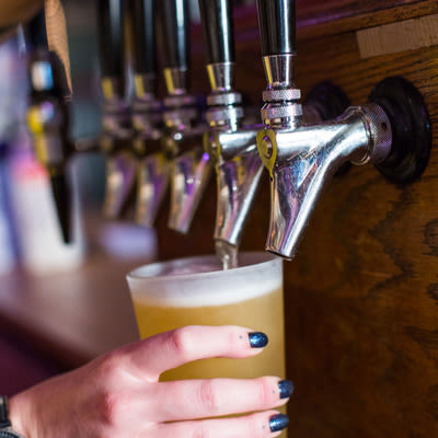 actively pouring a pint of a golden lager