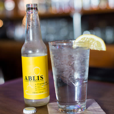 Ablis, a hemp derived, non-alcoholic, carbonated CBD beverage, garnished with a lemon wedge