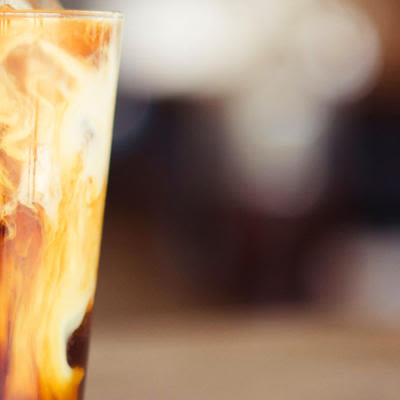 close up of a milk and coffee swirling in a pint glass