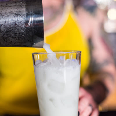 A bartender pouring the cocktail in a glass