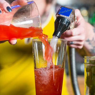 pouring campari from a tumbler into a pint glass and adding soda