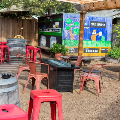 Mad Hanna patio gas fire pit, table and chairs and mural in the background
