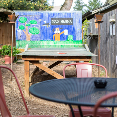 Mad Hanna patio with ping pong table, patio table and chairs, and Duck Hunt inspired mural in background