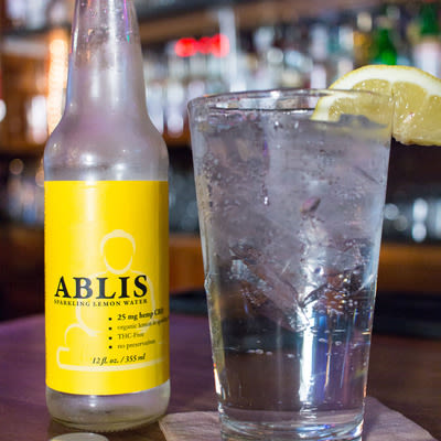 Ablis, a hemp derived, non-alcoholic, carbonated CBD beverage, garnished with a lemon wedge