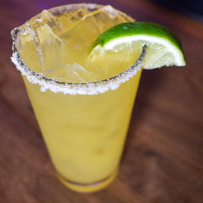 a fresh squeezed margarita with a salt rim and a lime wedge